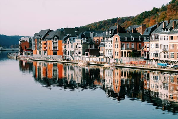 Belgium Alex Vasey - Unsplash Row of colourful houses in autumn in Belgium beside a lake.