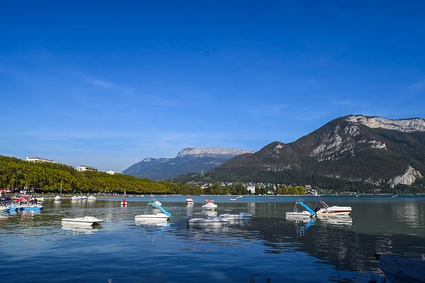 Boats on the water of Annecy Lake with mountains in the background.