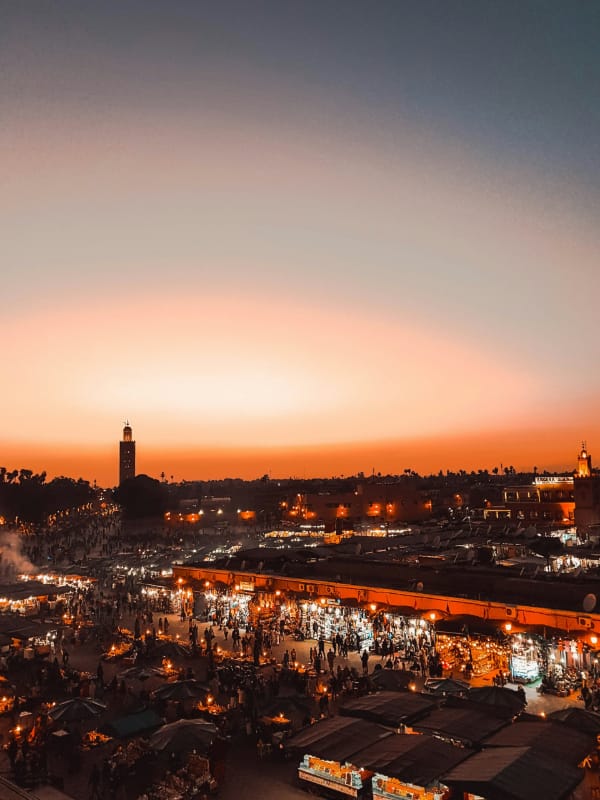 Marrakech Miltiadis Fragkidis Unsplash Orange hues in the sky and souks lit up in Marrakech with Koutoubia Mosque.